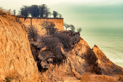 Rock formation on shore against sky