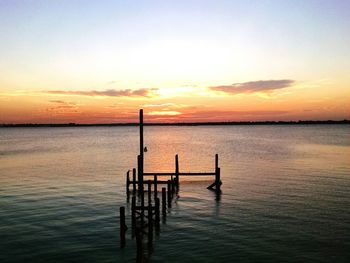 Pier in sea at sunset