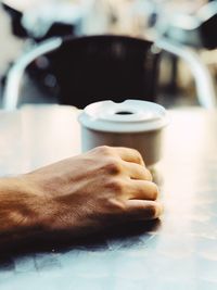 Cropped hand of man having coffee at table