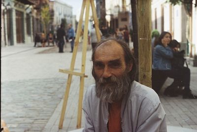 Portrait of homeless man sitting at city street