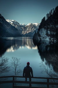 Rear view of man looking at lake against sky