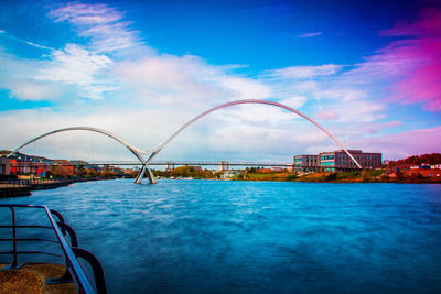 Bridge over river in city against sky