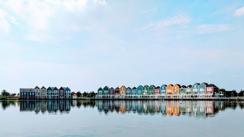 Houses by lake against sky