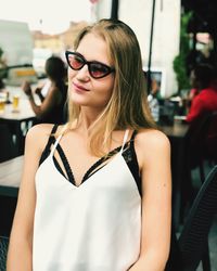 Young woman wearing sunglasses while sitting at outdoor restaurant