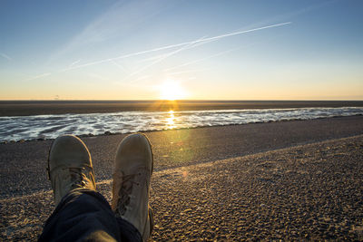 Low section of man at beach during sunset