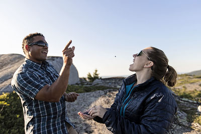 Black male throws blueberry in mouth of female friend on summit, maine