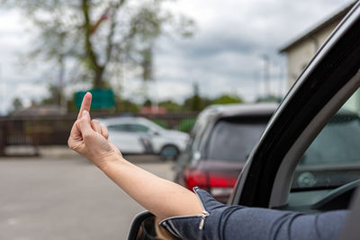 Rude and furious driver giving middle finger to car behind, woman shows obscene gesture from a car