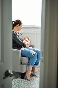 Mother and daughter sitting on sofa at home