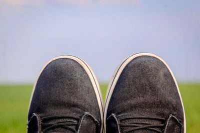 Low section of person wearing black shoes against clear sky