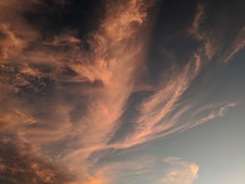 Low angle view of dramatic desert sky with swirly orange clouds at sunset