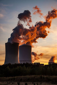 Smoke emitting from factory against sky during sunset