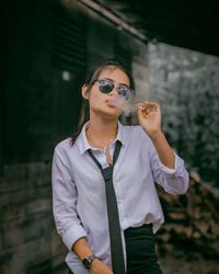 Portrait of young woman wearing sunglasses standing outdoors