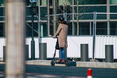 Rear view of woman walking against building in city