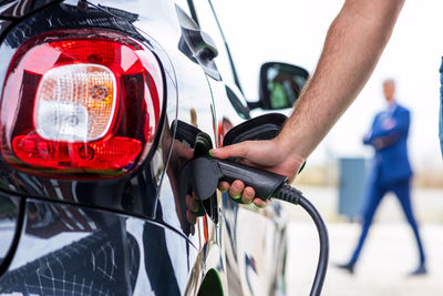 Electric car with plug-in socket at charge station charging battery