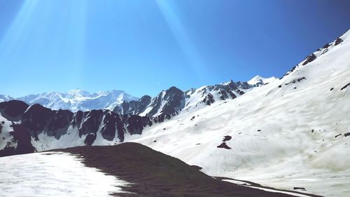 Scenic view of snowcapped mountains against clear blue sky