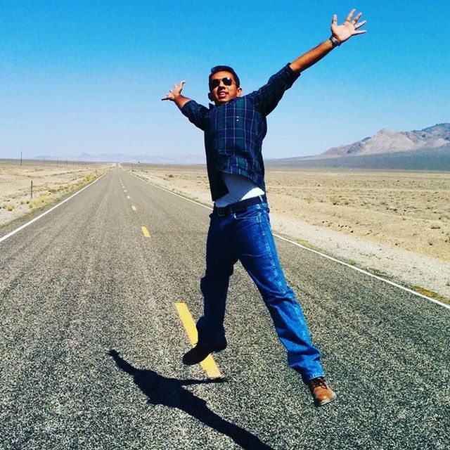 full length, lifestyles, person, casual clothing, leisure activity, young adult, front view, road, standing, sky, looking at camera, mid-air, clear sky, portrait, sunlight, arms outstretched, young men, happiness