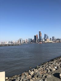 Sea by buildings against clear sky