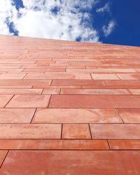 Low angle view of brick wall against cloudy sky