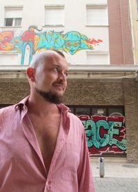 Low angle view of thoughtful mid adult man against graffiti building
