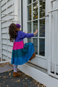 Rear view of girl standing against window