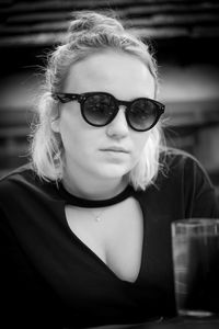 Portrait of young woman wearing sunglasses while sitting at table