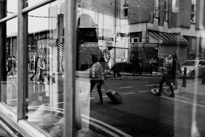 People on street reflecting on glass window