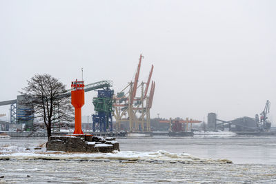 Harbor landscape with lighthouse and container cranes on a cold, foggy winter morning, riga, latvia