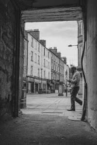 Side view of man walking on street amidst buildings