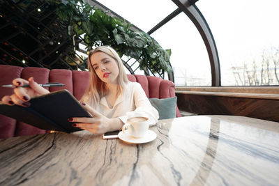 Young woman using mobile phone while sitting on table