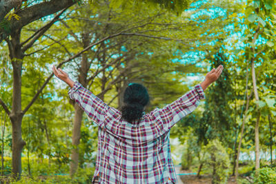 Rear view of woman standing in forest