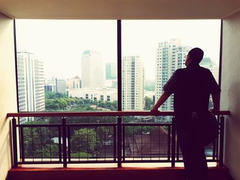 Rear view of man standing by window