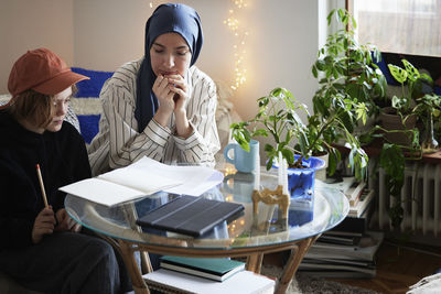 Mother wearing hijab helping son doing homework