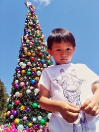 Low angle view of boy standing against christmas tree