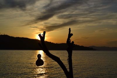 Silhouette people in lake against sky during sunset