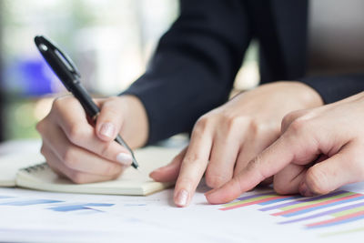 Midsection of woman holding paper while sitting on table