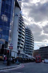 Cars on road by buildings against sky in city