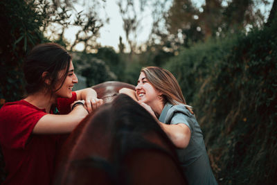 Smiling women with horse standing outdoors