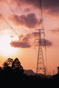 Low angle view of silhouette electricity pylon against sky during sunset