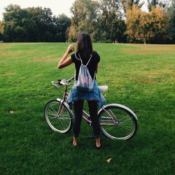 Rear view of woman with bicycle on field