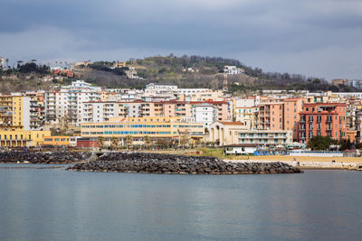 Aerial view of townscape by sea against sky