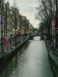 Canal amidst buildings in city against sky