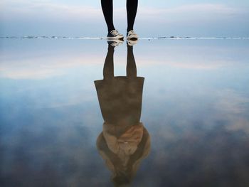 Low section of woman standing by her reflection of lake