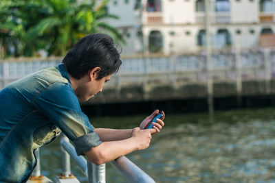Side view of young man using mobile phone