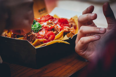 Cropped hand of person eating food on table