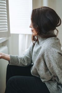 Side view of young woman sitting on sofa at home