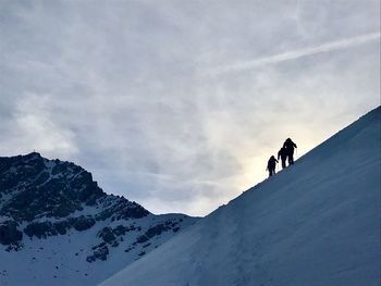 People on snowcapped mountain against sky