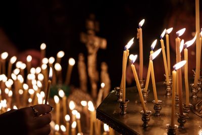 Cropped image of hand burning candles in church