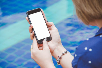 Cropped hands of woman using mobile phone at poolside