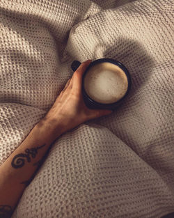 High angle view of person holding coffee cup on textile