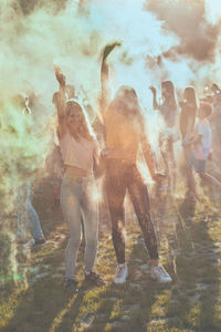 Happy friends playing with powder paint while standing outdoors